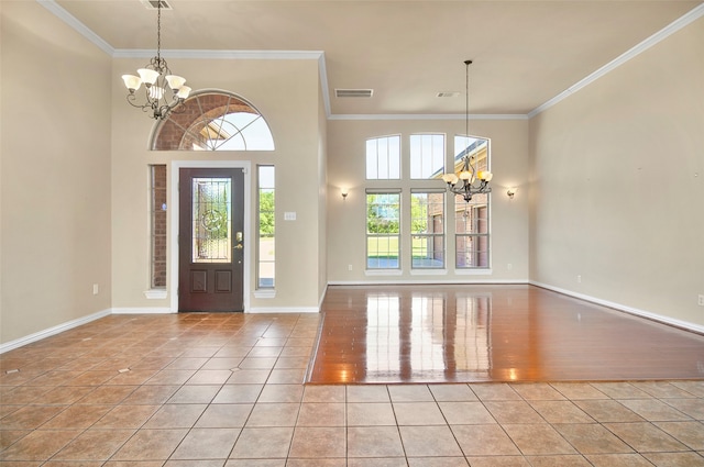 tiled foyer entrance featuring plenty of natural light, a chandelier, and crown molding