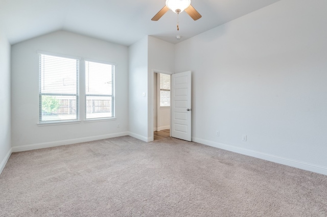 empty room featuring lofted ceiling, ceiling fan, and light colored carpet