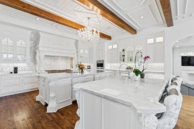 kitchen featuring white cabinetry, sink, dark hardwood / wood-style floors, backsplash, and a spacious island