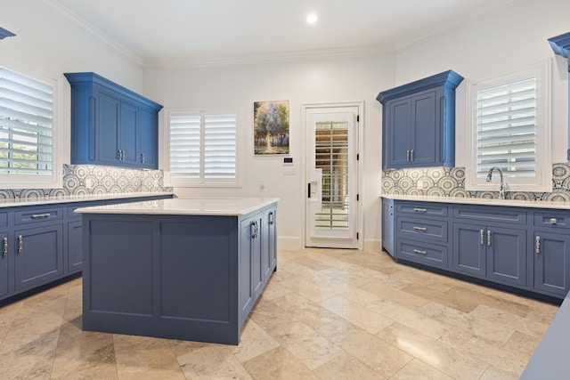 kitchen with blue cabinets, backsplash, crown molding, and a center island