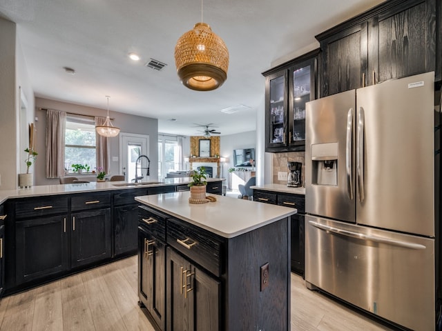 kitchen featuring stainless steel fridge, sink, a kitchen island, a fireplace, and light wood-type flooring