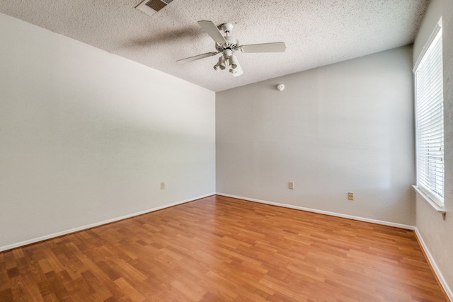 empty room with ceiling fan, light hardwood / wood-style flooring, and a textured ceiling