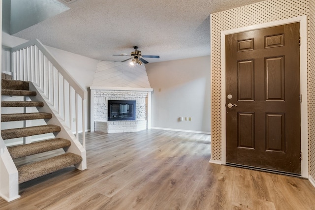 unfurnished living room featuring lofted ceiling, ceiling fan, light wood-type flooring, and a textured ceiling