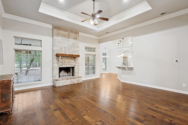 unfurnished living room with a stone fireplace, dark hardwood / wood-style flooring, and a tray ceiling