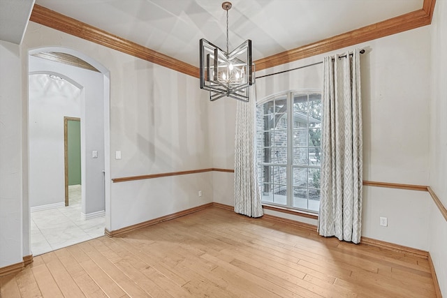 empty room featuring ornamental molding, wood-type flooring, and a chandelier