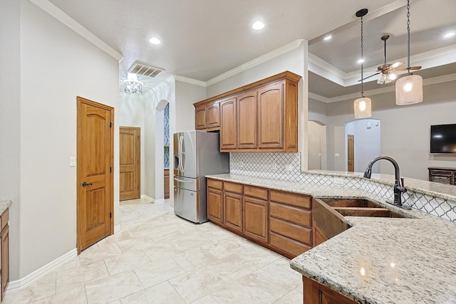 kitchen with sink, light stone counters, stainless steel refrigerator with ice dispenser, hanging light fixtures, and decorative backsplash