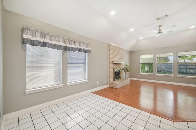 unfurnished living room featuring ceiling fan, light hardwood / wood-style floors, lofted ceiling, and a brick fireplace