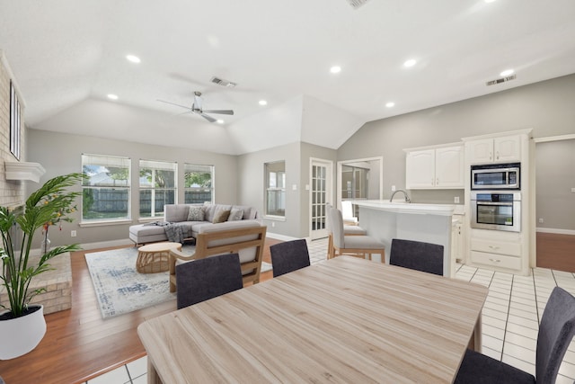 dining room with sink, vaulted ceiling, ceiling fan, and light tile patterned flooring