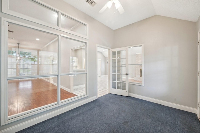 empty room featuring french doors, dark carpet, a textured ceiling, vaulted ceiling, and ceiling fan