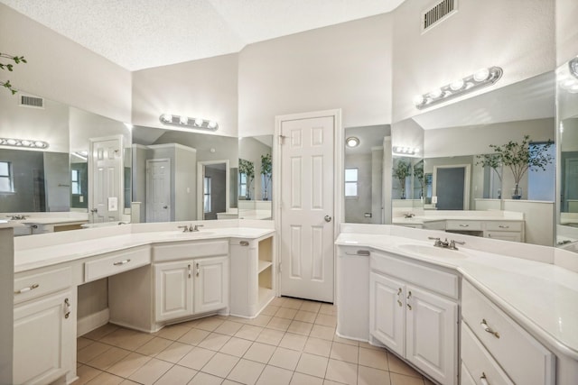 bathroom with tile patterned flooring, vanity, a textured ceiling, and a high ceiling