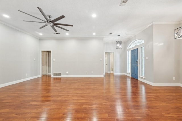 spare room featuring hardwood / wood-style floors, ceiling fan with notable chandelier, ornamental molding, and a textured ceiling