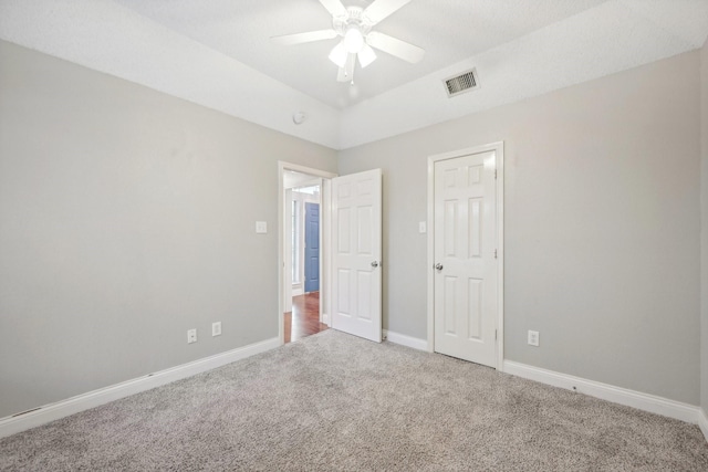 unfurnished bedroom with carpet flooring, ceiling fan, and a tray ceiling