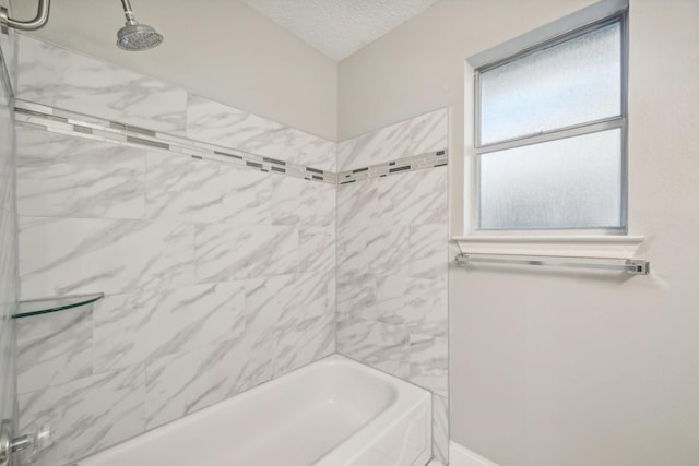 bathroom with a textured ceiling and tiled shower / bath combo