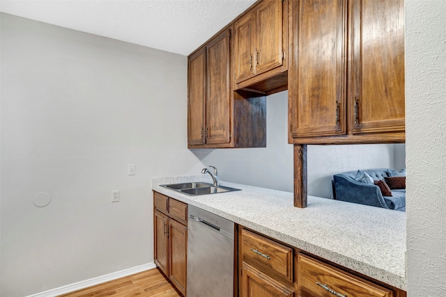 kitchen featuring light wood-type flooring, dishwasher, a textured ceiling, and sink