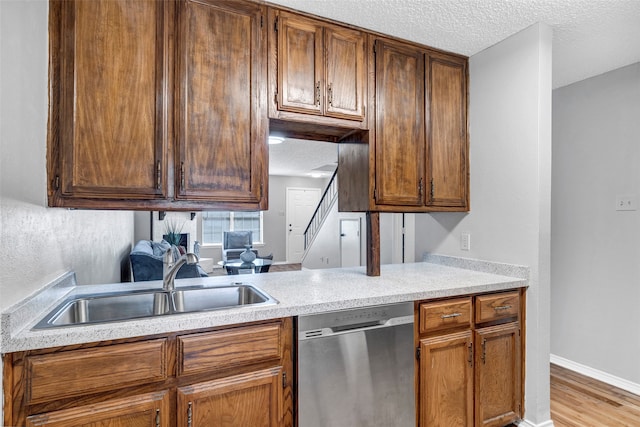 kitchen with dishwasher, light hardwood / wood-style flooring, sink, and a textured ceiling