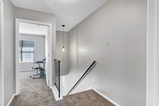 stairway with carpet and a textured ceiling