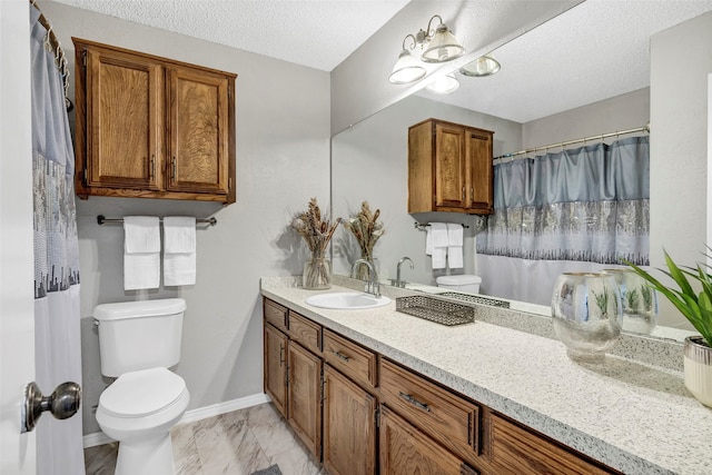 bathroom with a textured ceiling, vanity, and toilet