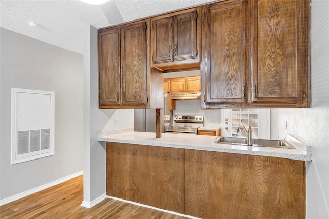 kitchen featuring stainless steel range with electric cooktop, light wood-type flooring, a textured ceiling, and sink