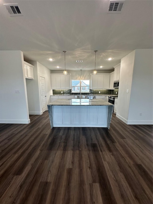 kitchen featuring hanging light fixtures, a kitchen island, stainless steel appliances, decorative backsplash, and white cabinets