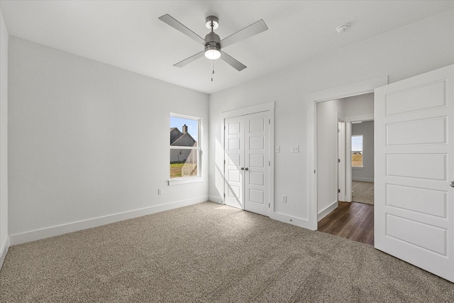 unfurnished bedroom with a closet, ceiling fan, and dark colored carpet