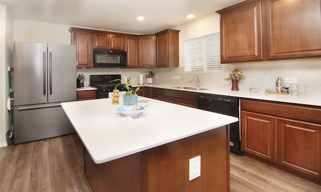 kitchen with black appliances, a kitchen island, sink, and wood-type flooring