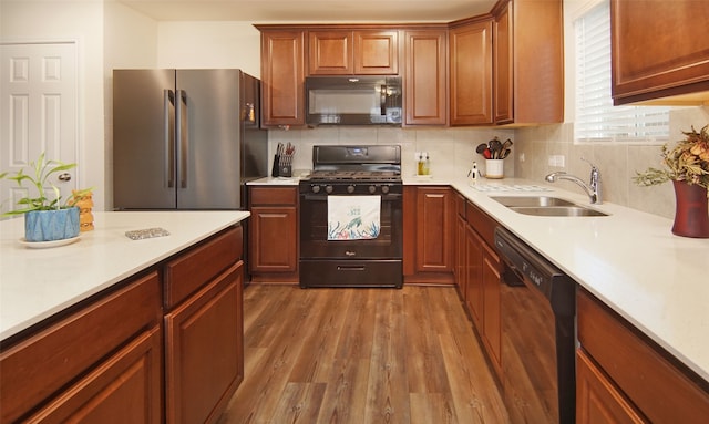 kitchen with decorative backsplash, wood-type flooring, black appliances, and sink