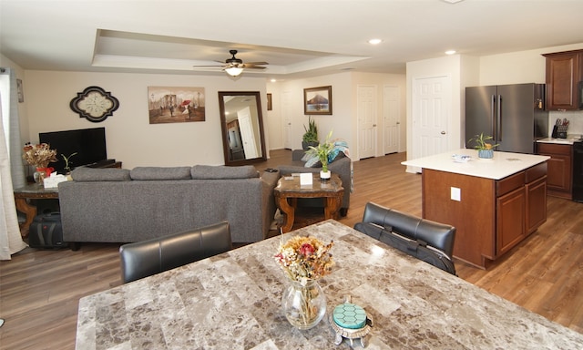 dining area featuring ceiling fan, a raised ceiling, and dark hardwood / wood-style flooring