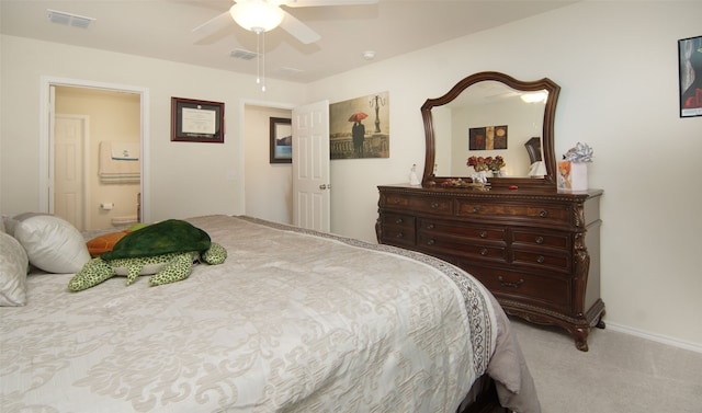 carpeted bedroom with ensuite bath and ceiling fan