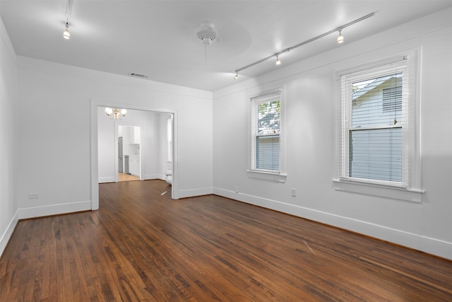 empty room featuring rail lighting and dark wood-type flooring