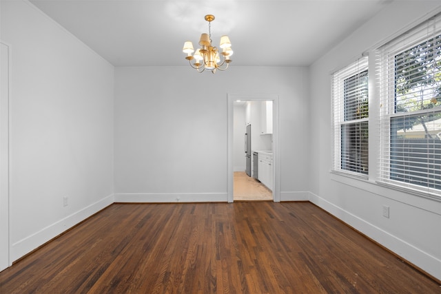 spare room featuring an inviting chandelier and dark hardwood / wood-style flooring