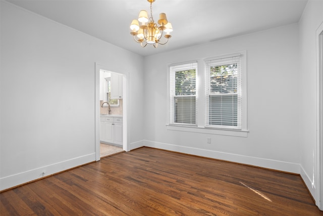 spare room featuring an inviting chandelier and dark hardwood / wood-style flooring