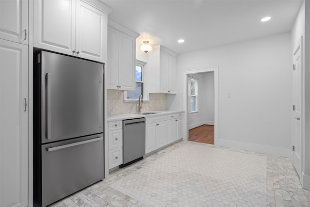 kitchen featuring stainless steel appliances, white cabinets, sink, and backsplash