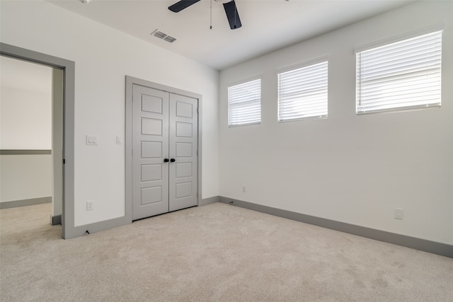 unfurnished bedroom with ceiling fan, light colored carpet, and a closet