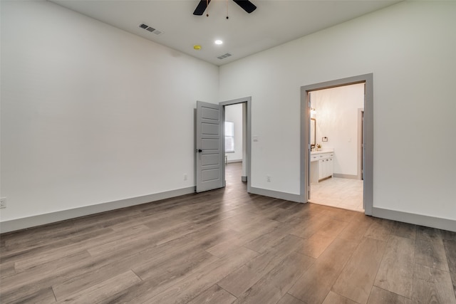 unfurnished bedroom featuring ceiling fan, ensuite bath, and light hardwood / wood-style floors