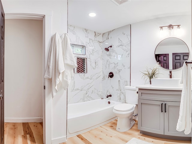 full bathroom featuring vanity, hardwood / wood-style flooring, tiled shower / bath, and toilet