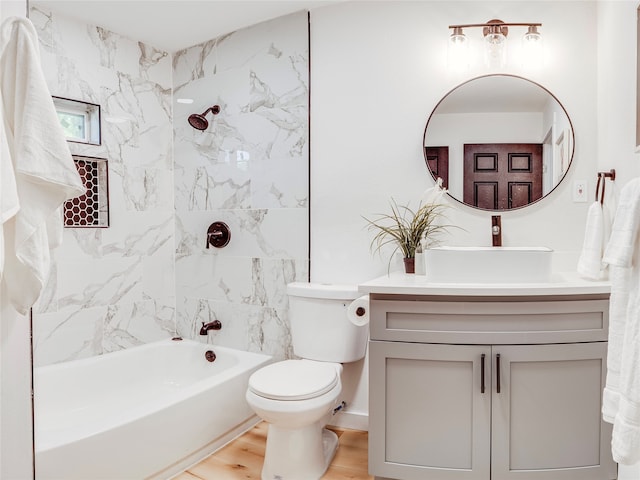 full bathroom with wood-type flooring, vanity, tiled shower / bath, and toilet