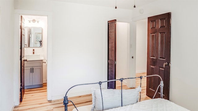 bedroom with light wood-type flooring and connected bathroom