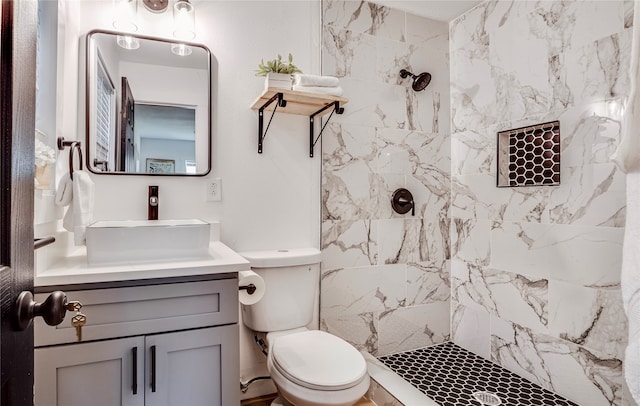 bathroom with a tile shower, vanity, and toilet