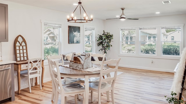 dining area with light wood-type flooring, ceiling fan with notable chandelier, and plenty of natural light