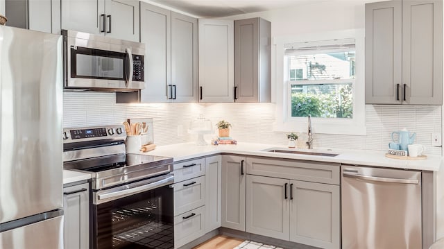 kitchen featuring gray cabinets, appliances with stainless steel finishes, sink, and decorative backsplash