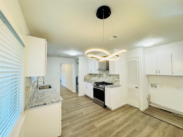 kitchen featuring tasteful backsplash, stainless steel range, sink, decorative light fixtures, and white cabinets