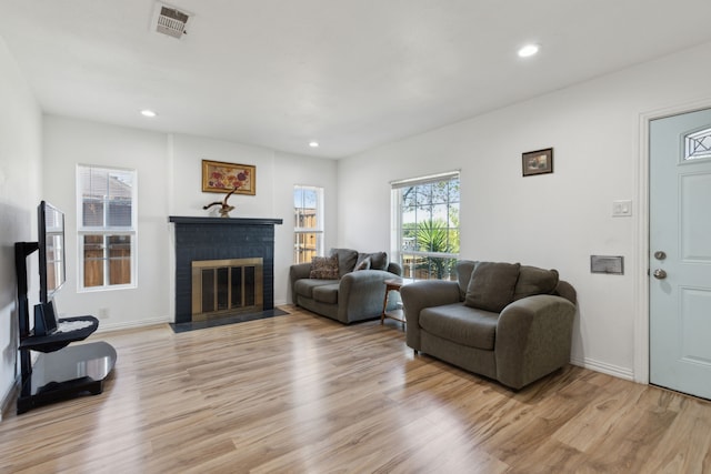 living room with a brick fireplace and light wood-type flooring