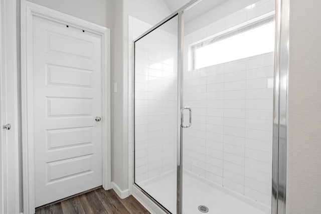 bathroom with a shower with shower door and hardwood / wood-style floors