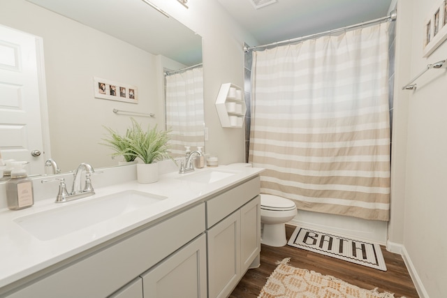 bathroom featuring wood-type flooring, curtained shower, vanity, and toilet