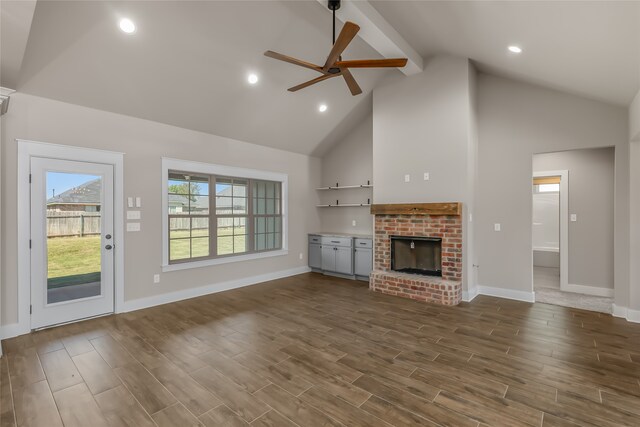 unfurnished living room featuring ceiling fan, a fireplace, dark wood-type flooring, and high vaulted ceiling