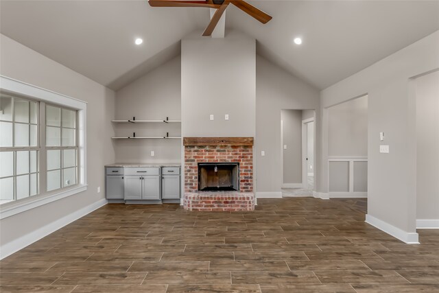 unfurnished living room featuring a fireplace, dark hardwood / wood-style floors, ceiling fan, and high vaulted ceiling