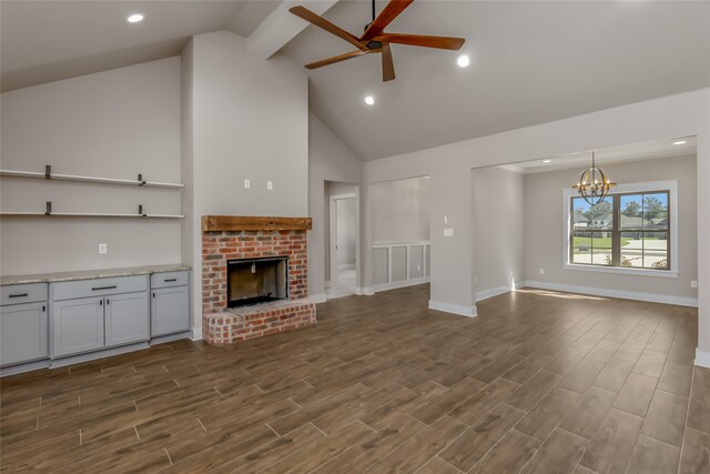 unfurnished living room featuring ceiling fan with notable chandelier, a fireplace, dark hardwood / wood-style floors, and high vaulted ceiling