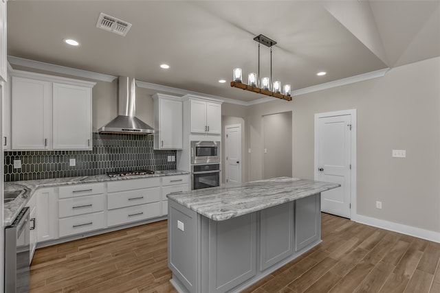 kitchen with a kitchen island, light hardwood / wood-style flooring, wall chimney exhaust hood, white cabinetry, and stainless steel appliances