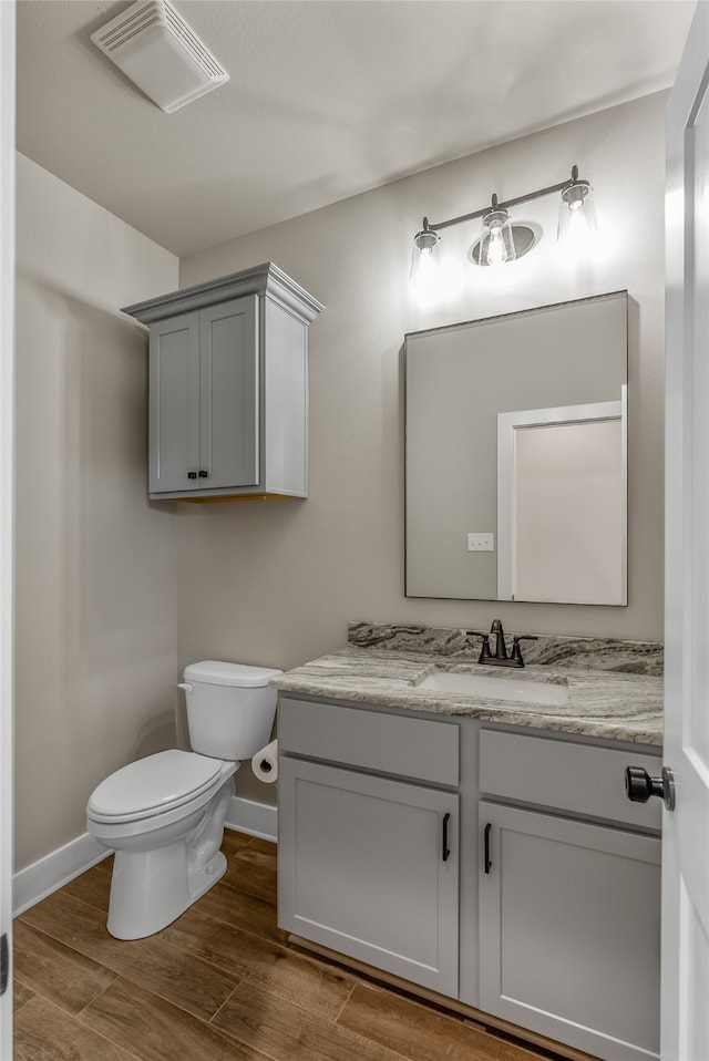 bathroom with wood-type flooring, vanity, and toilet