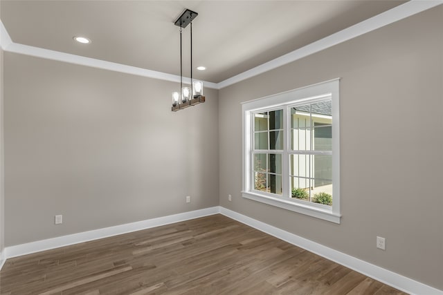 empty room with a notable chandelier, dark hardwood / wood-style floors, and ornamental molding